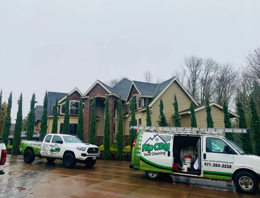 Rip City Roof Cleaning vehicles at a residential work site in wet weather