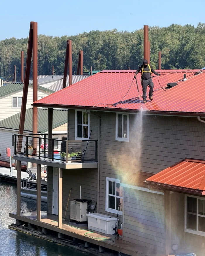 Rip City Roof Cleaning technician cleaning a red metal roof